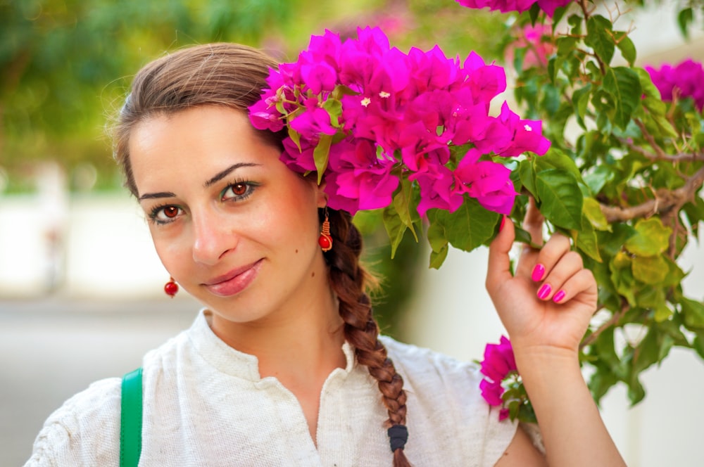 woman wearing white top holding pink flower