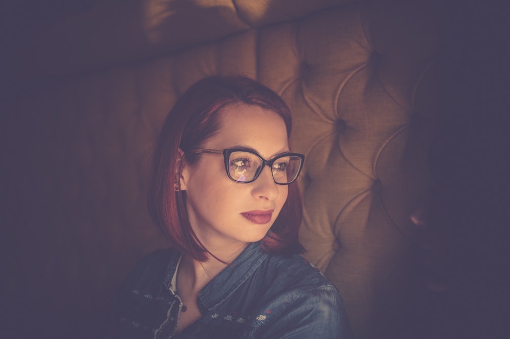 woman wearing blue top and black framed eyeglasses