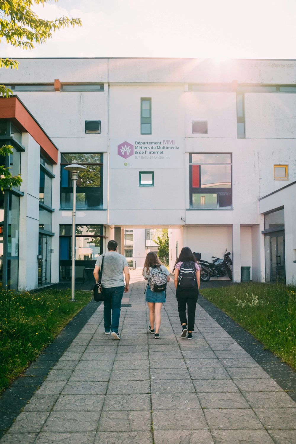 two women and 1 men walking on concrete pathway