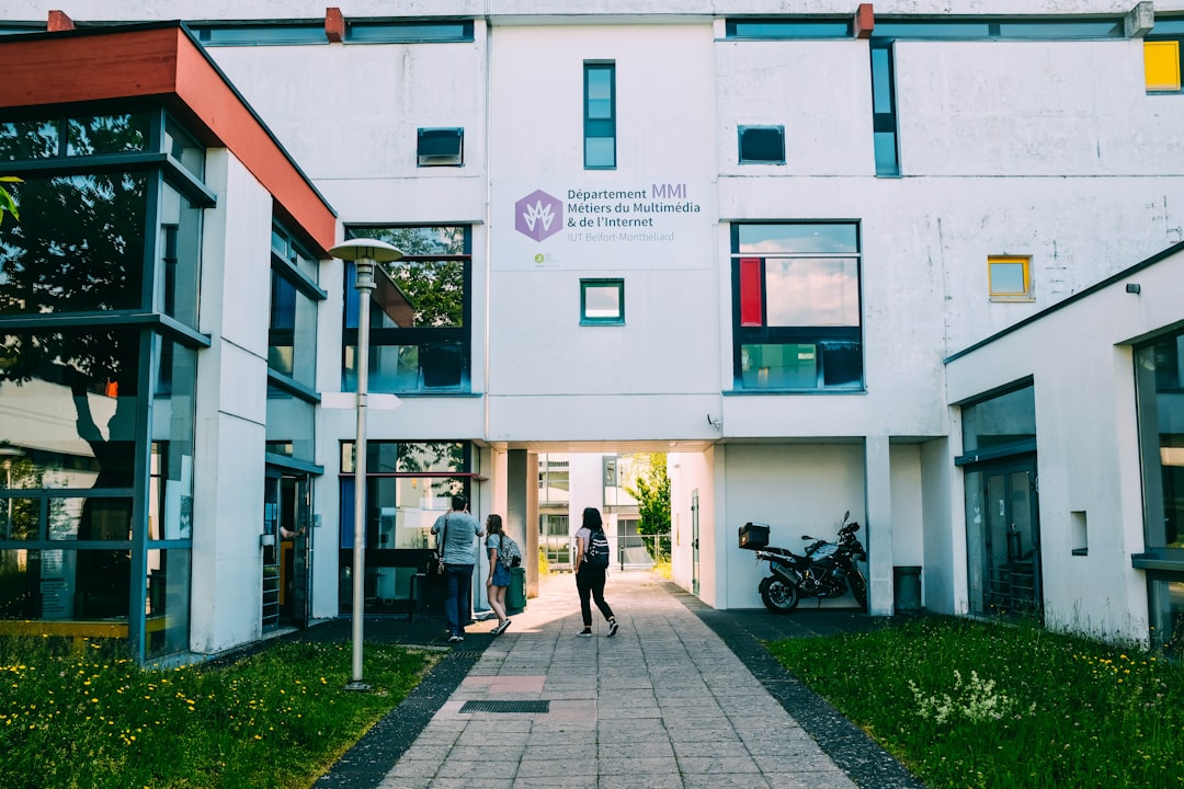 two women standing beside white building during daytime