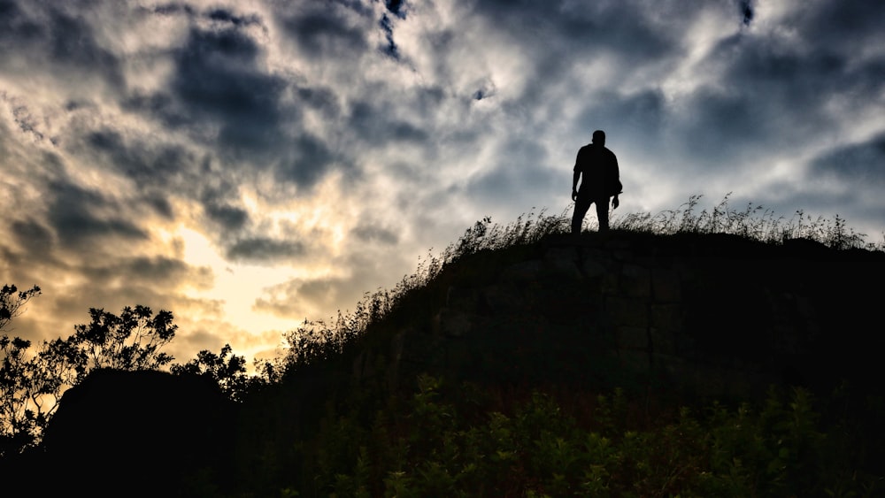 silhouette photography of person standing on hill
