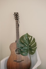Acoustic guitar resting against a rustic wooden chair.