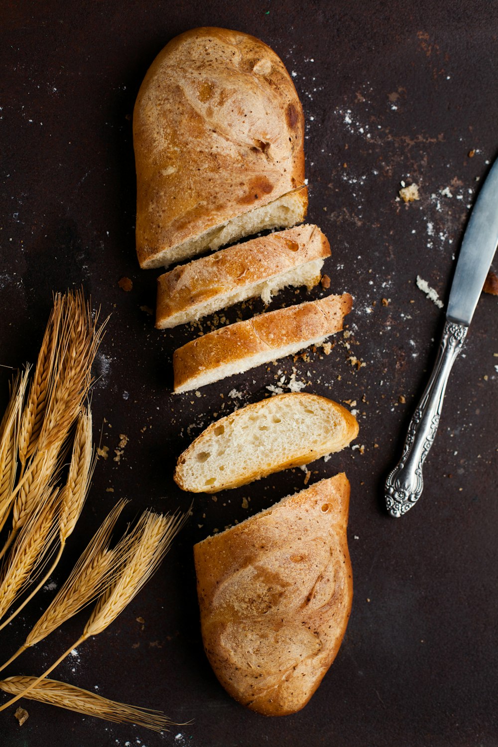 fatiado de pão assado ao lado de faca de pão de aço inoxidável