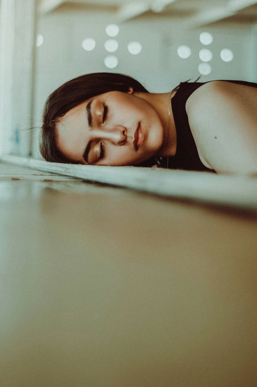 femme posant sa tête sur un lit à panneaux de bois brun tout en fermant les yeux
