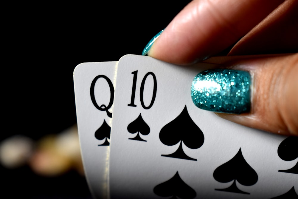 close-up photo of person holding two spade playing cards