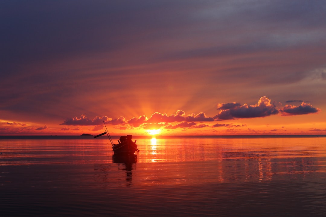 black boat on sea during golden hour