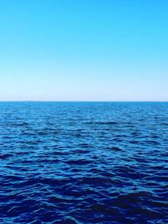 Close-up of a deep blue ocean wave under a clear sky, symbolizing purity and depth.