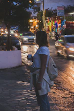 Close-up of hands exchanging a bottle of water and a blanket wrapped in orange accents, illuminated by urban street glow at night.