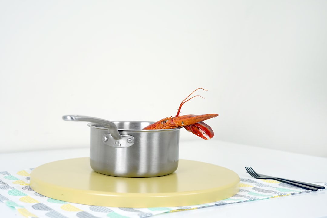 cooked lobster on gray stainless steel pot near gray stainless steel fork