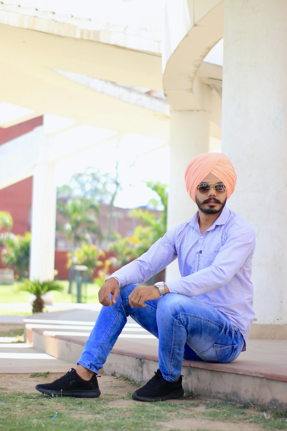 man in purple dress shirt and blue denim jeans sitting