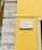 A street sign is mounted on a vibrant yellow wall next to a section of exposed stonework on a building. The sign reads 'Rua da Conceição da Glória' and is attached to the wall with visible screws.