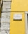 A street sign is mounted on a vibrant yellow wall next to a section of exposed stonework on a building. The sign reads 'Rua da Conceição da Glória' and is attached to the wall with visible screws.