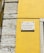 A street sign is mounted on a vibrant yellow wall next to a section of exposed stonework on a building. The sign reads 'Rua da Conceição da Glória' and is attached to the wall with visible screws.
