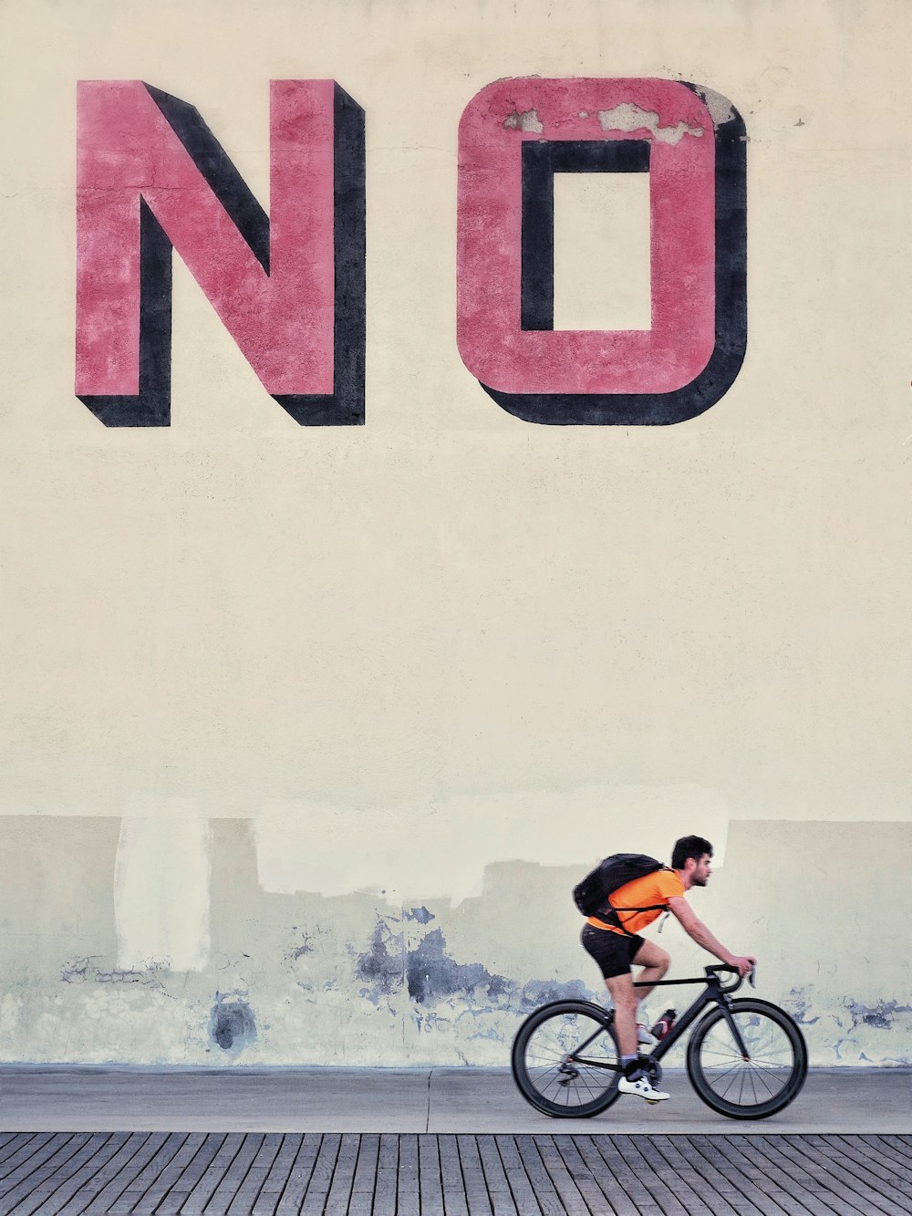 man riding bicycle beside wall with no text