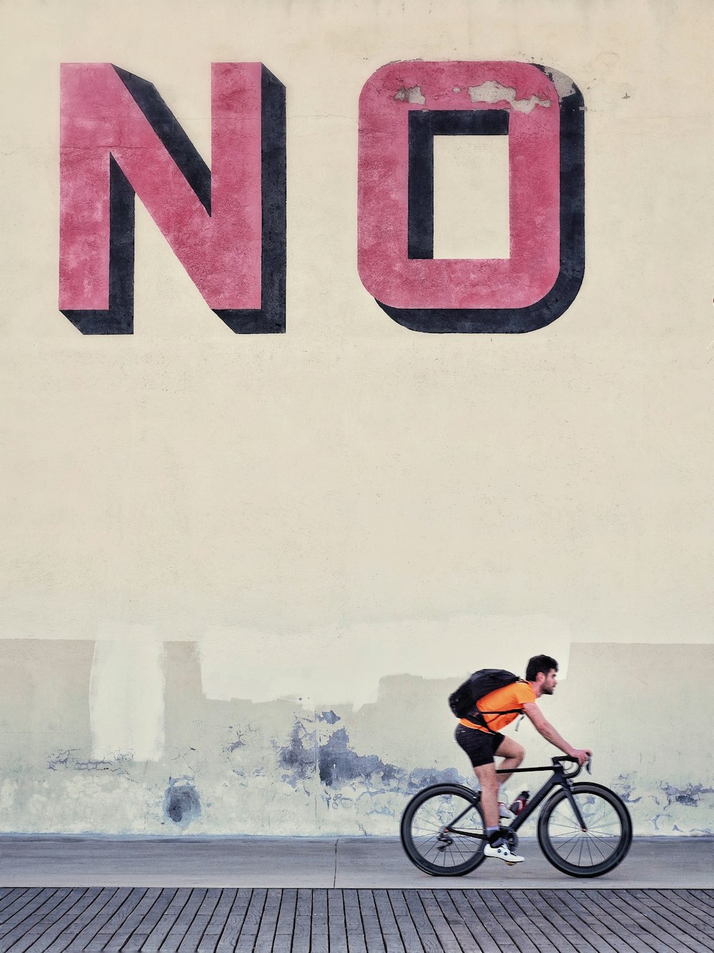 hombre montando en bicicleta al lado de la pared sin texto