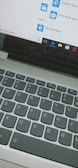 A close-up view of a laptop keyboard and a computer screen displaying the start menu with icons for Internet Explorer and Microsoft Edge, along with a search bar entry point.