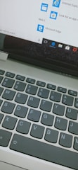 A close-up view of a laptop keyboard and a computer screen displaying the start menu with icons for Internet Explorer and Microsoft Edge, along with a search bar entry point.