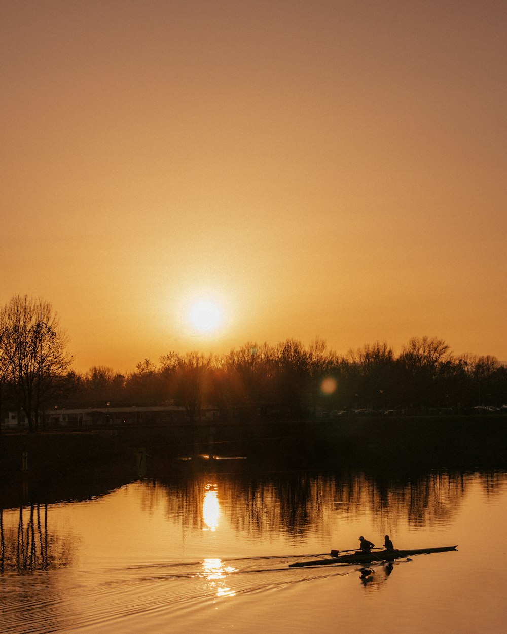 people riding boat at the lake during golden hour