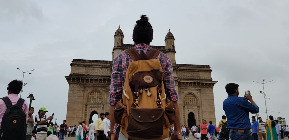 person with brown backpack walking towards brown church building