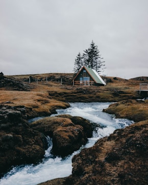 river near house under gray sky