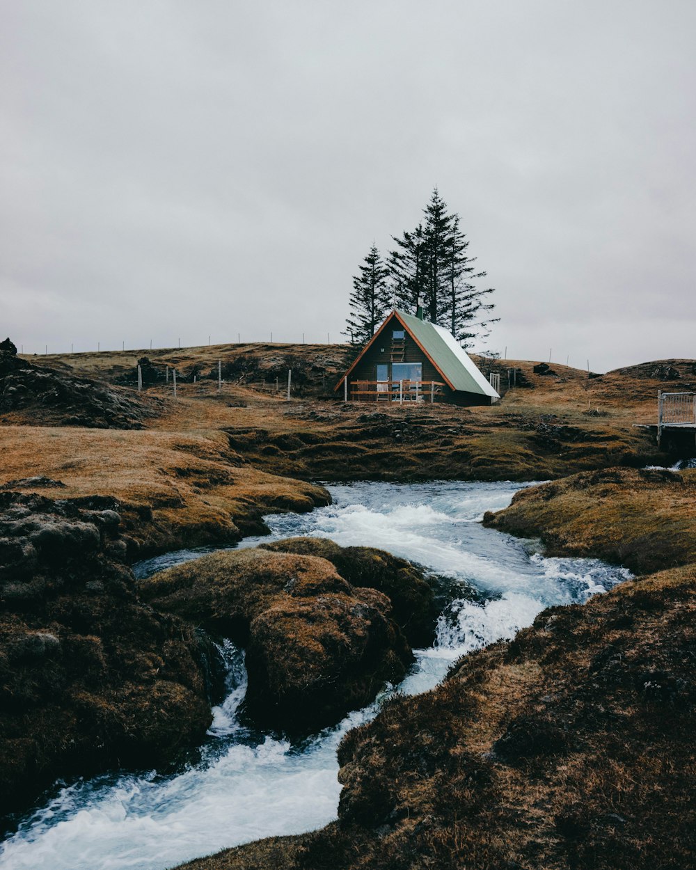 river near house under gray sky