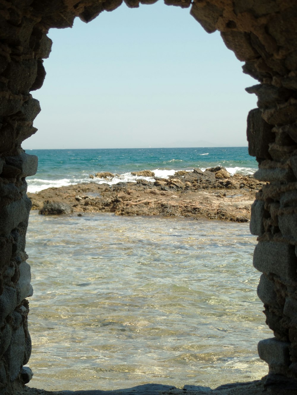 rock formation near blue sea under blue skies