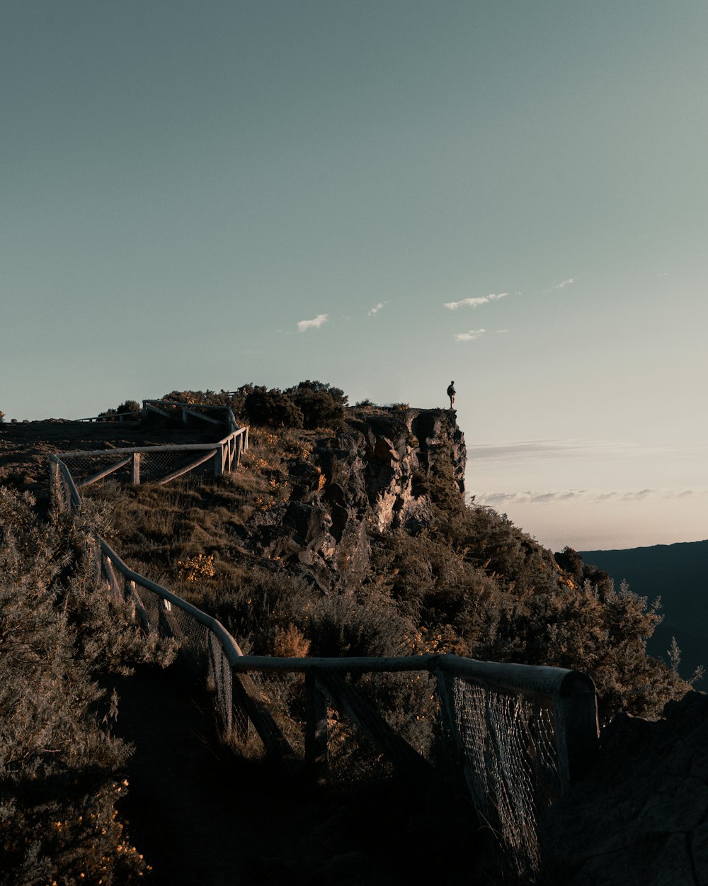 person standing on cliff viewing mountain