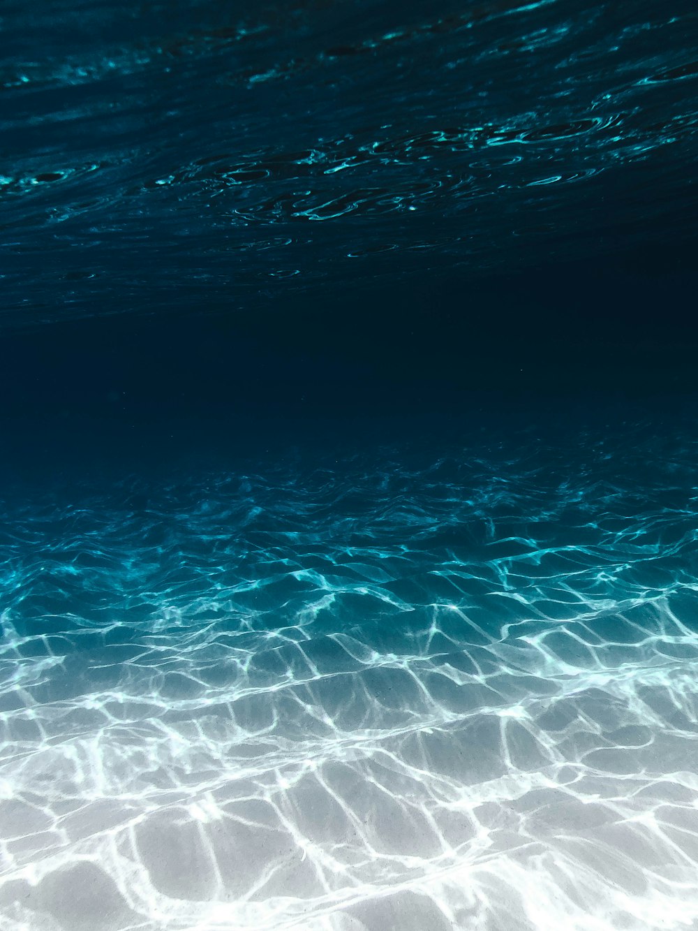 sabbia grigia sotto l'acqua limpida blu