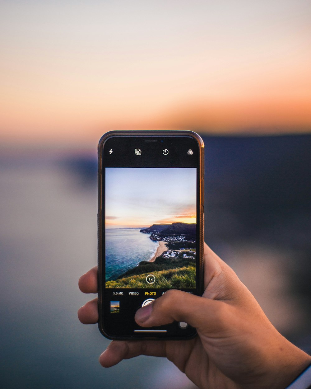 person holding black smartphone taking island photo