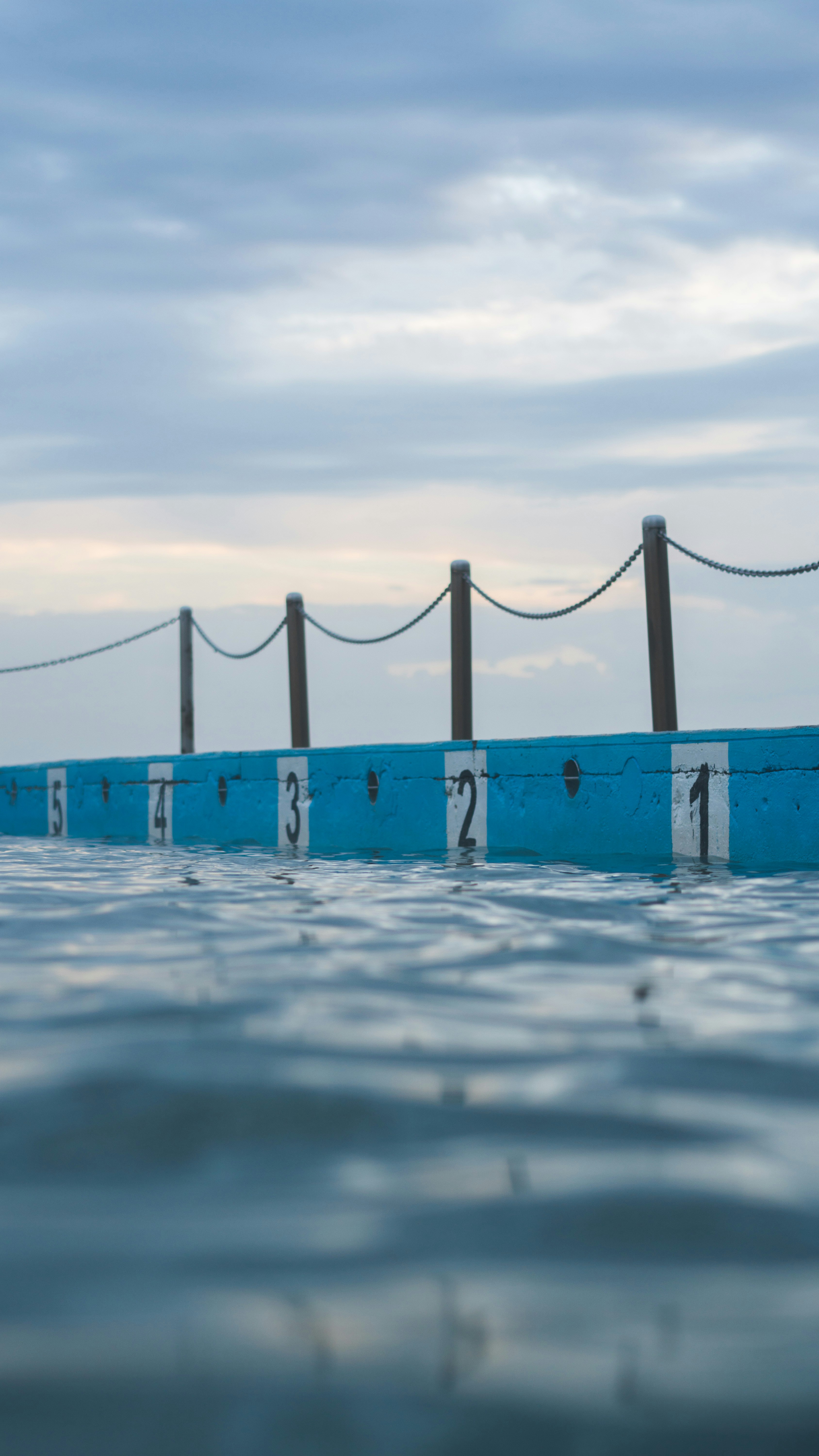 Outdoor swimming pool beside the ocean at dusk, cinematic editorial scene