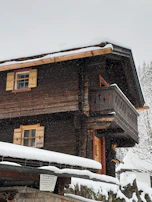 Finished wooden home exterior showcasing craftsmanship with snow gently falling.