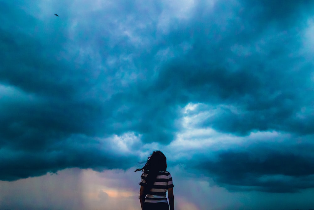 Persona con camisa de rayas blancas y negras a través de nubes azules