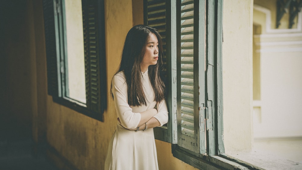 woman wearing white long-sleeved shirt besides window