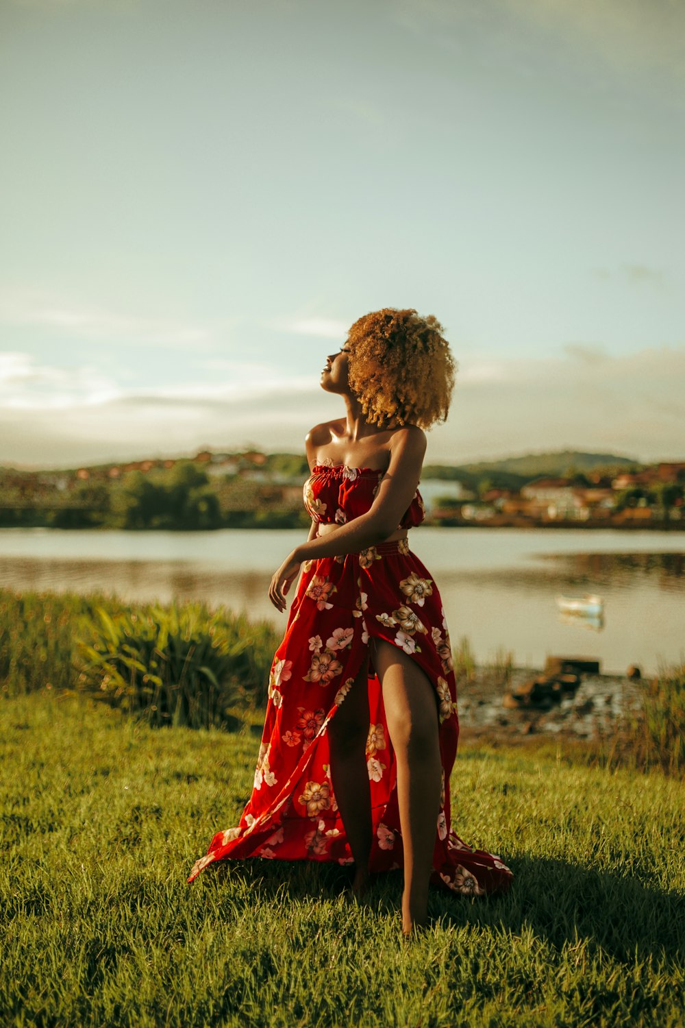 woman wearing white and red floral tube dress standing on green grass field outdoor during daytime