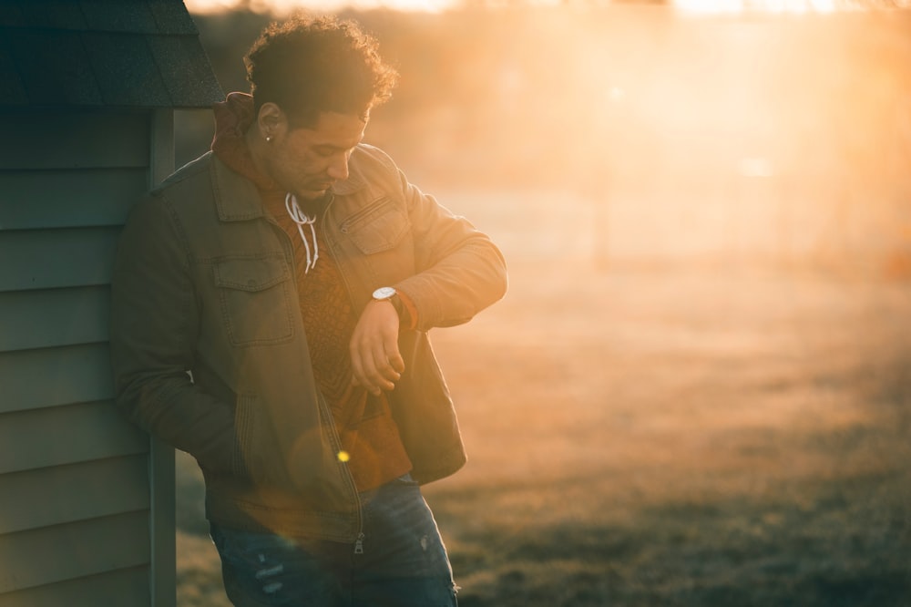 man checking the time while leaning on shed