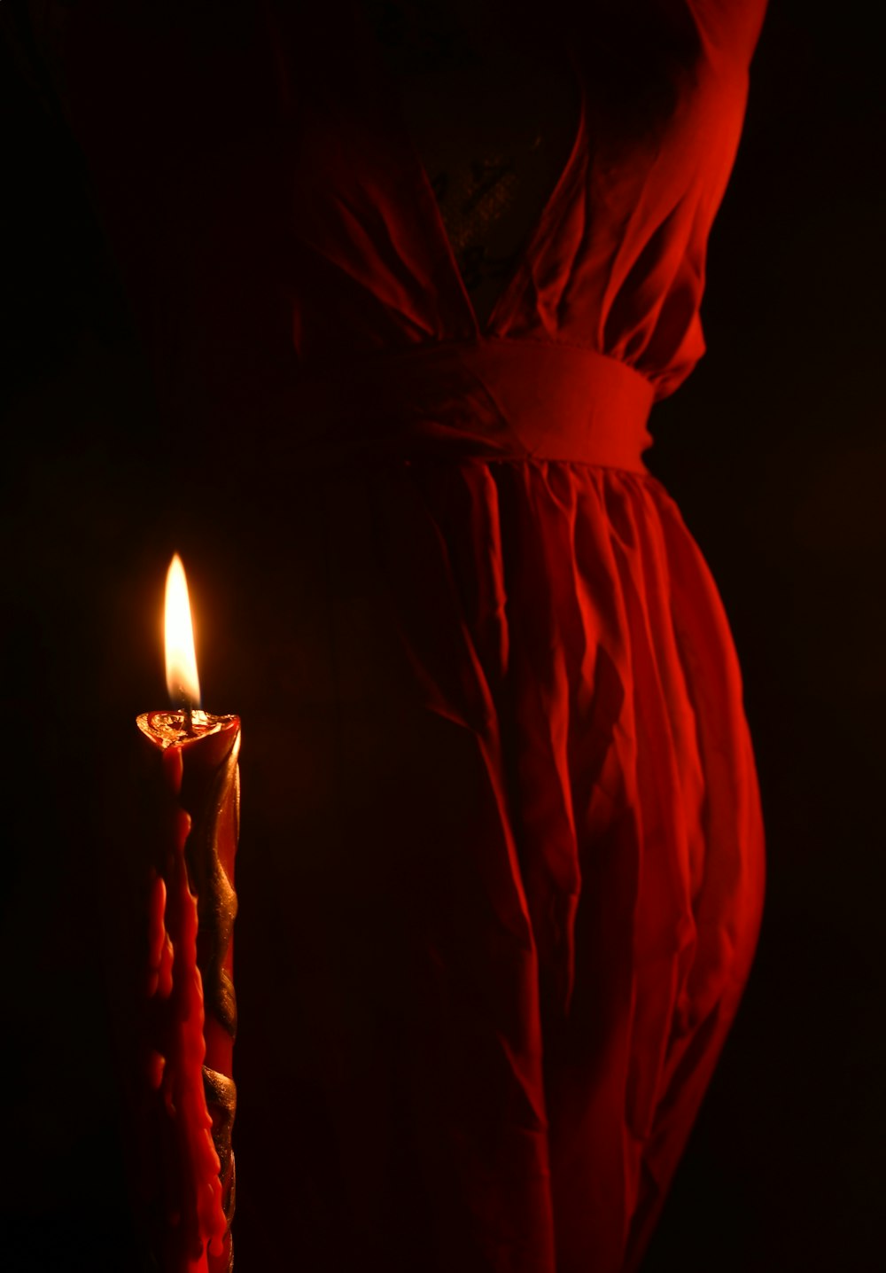 lighted candle near red textile