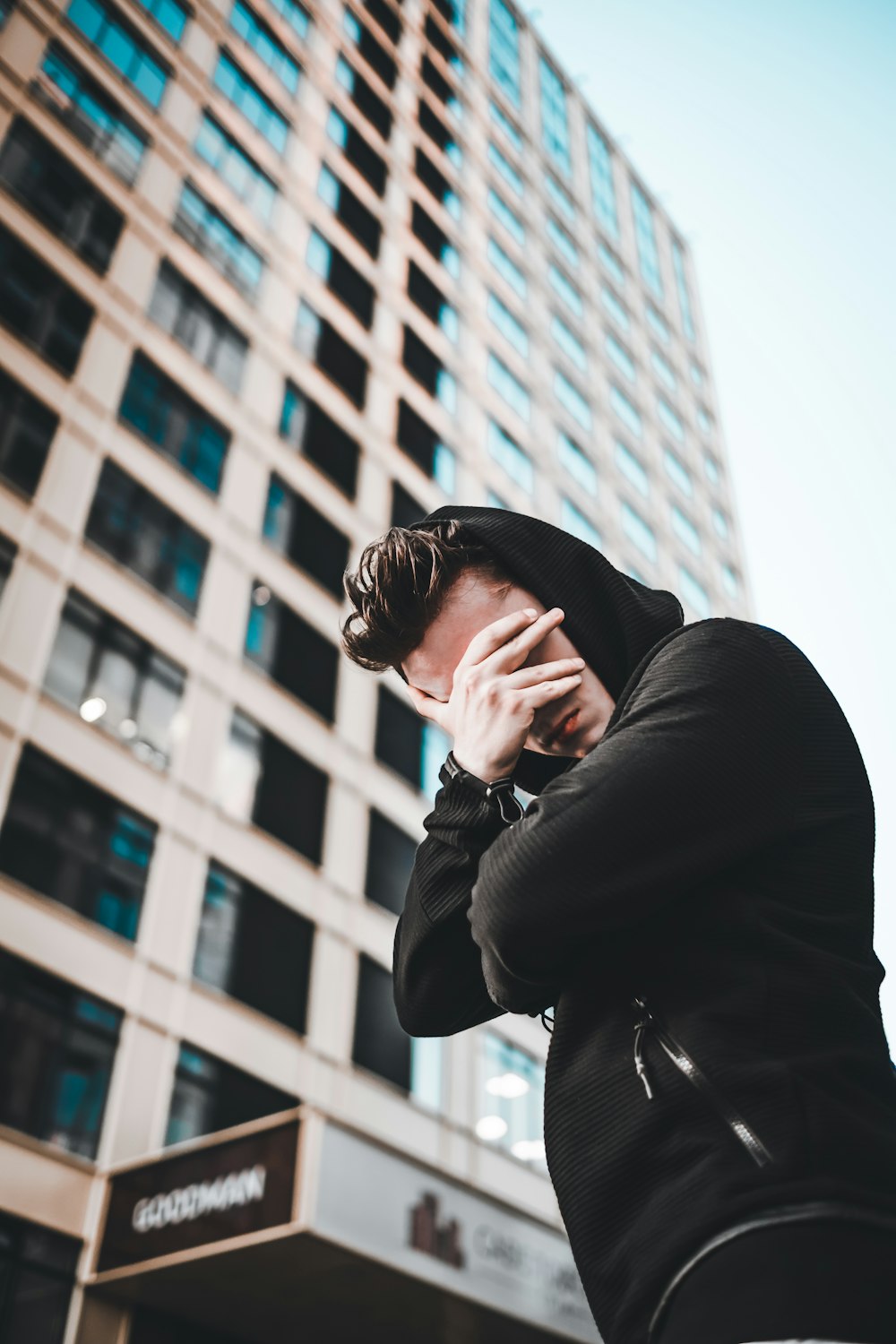 man wearing black jacket standing in front of building