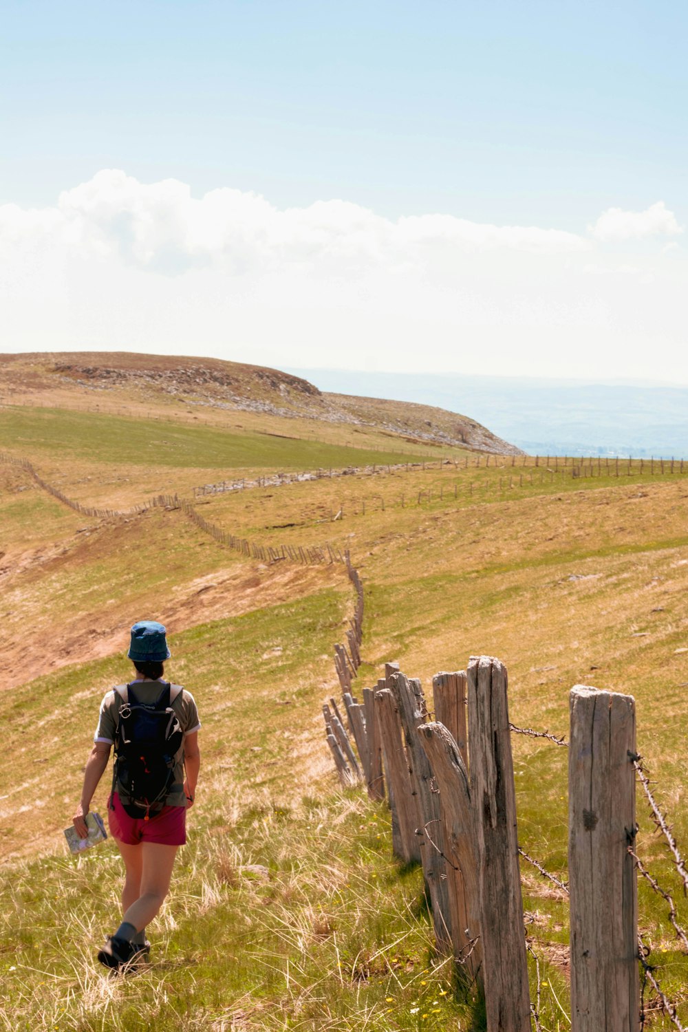 woman carrying backpack walking beside fence