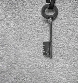 A vintage-style key resting on a textured red and black background.