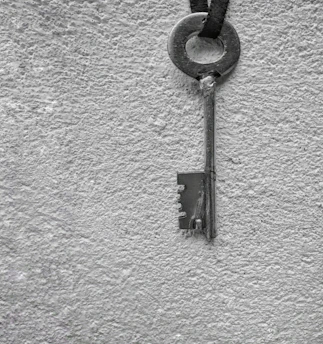 A vintage-style key resting on a textured red and black background.