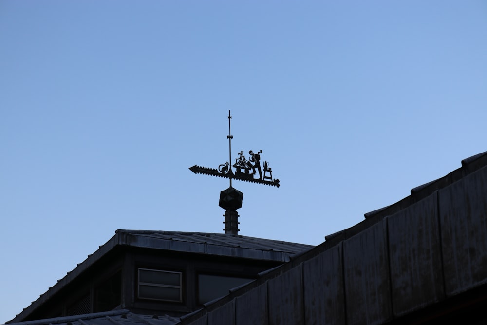 wind vane on rooftop under clear blue sky