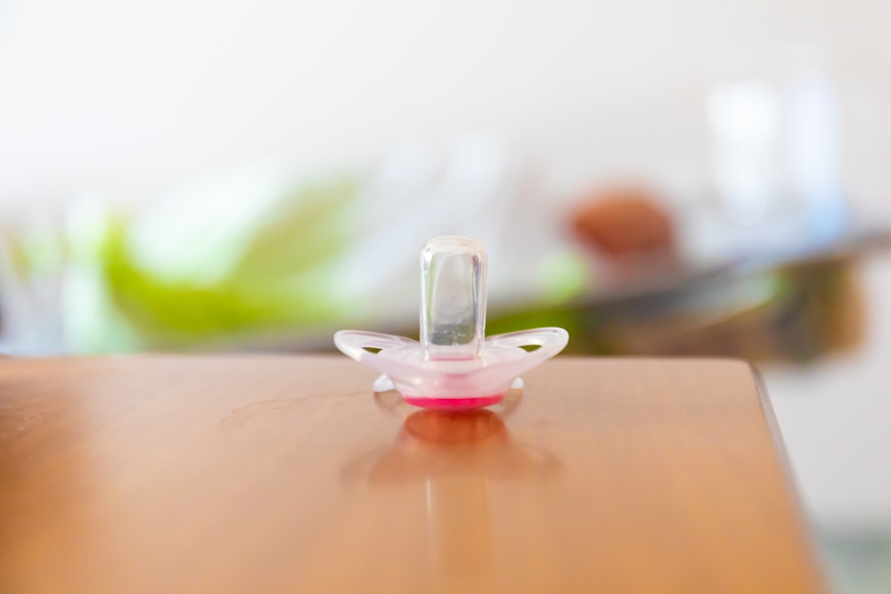 red and white pacifier on brown wooden surface