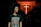 A person with curly hair is wearing a black t-shirt with the text 'John 10:10 JESUS DIED SO I COULD LIVE' in a dimly lit environment. In the background, there is a prominent glowing red cross on the wall.