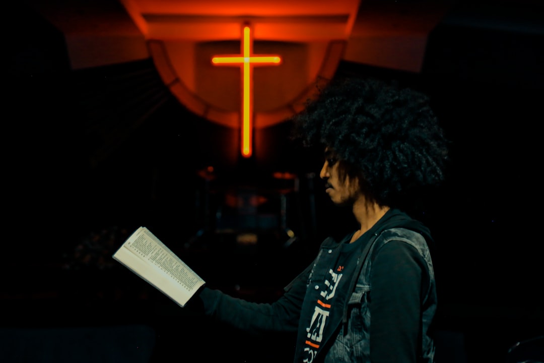 man wearing black and gray jacket holding book