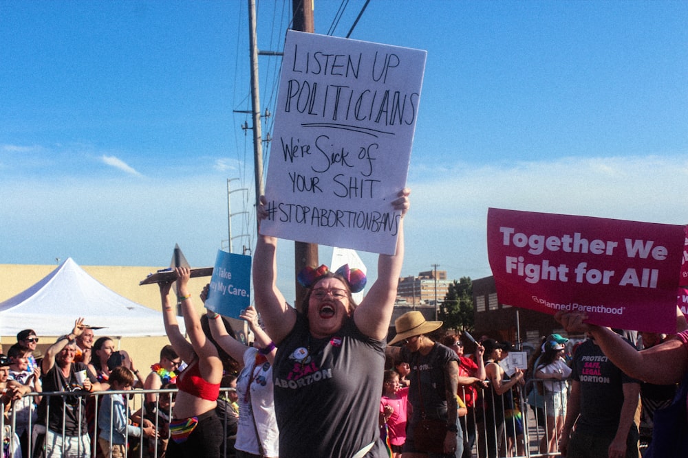 woman raising listen up politicians sign on road