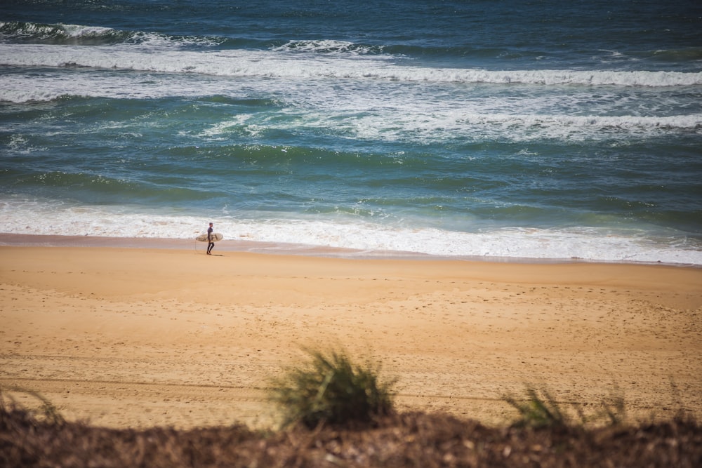 uomo con tavola da surf che cammina in spiaggia