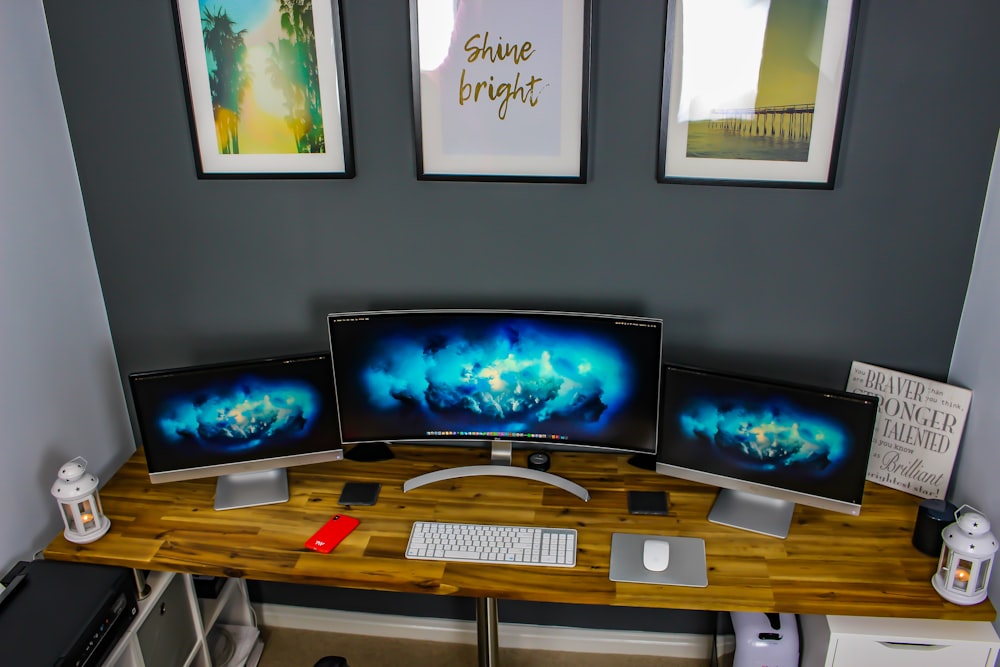 three flat screen computer monitor on desk