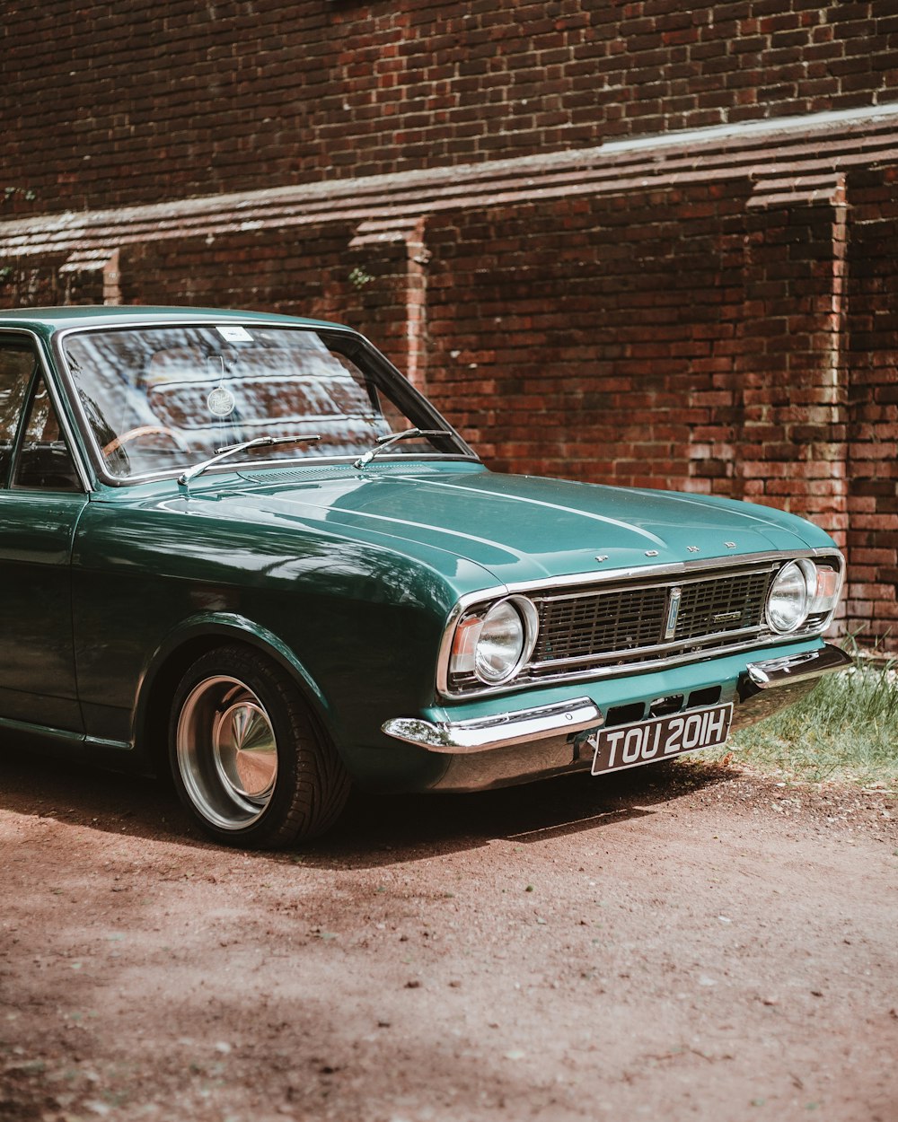 green car besides brown brick wall