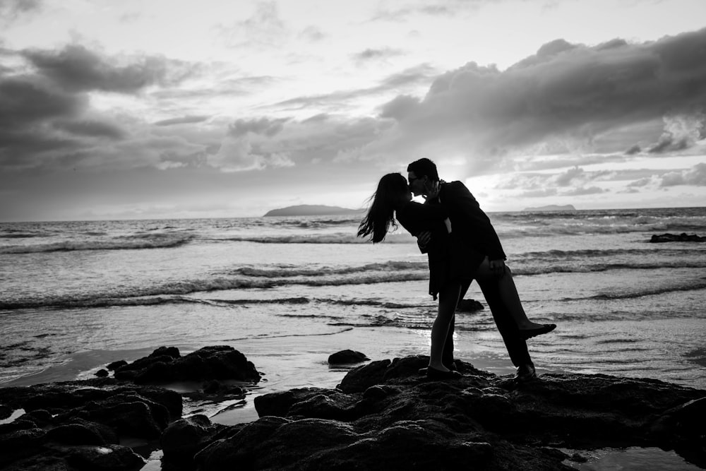 silhouette photo of man and woman kissing near body of water