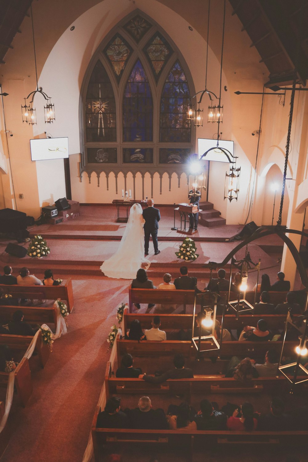 man and woman standing on altar in front of people sitting on pews inside church